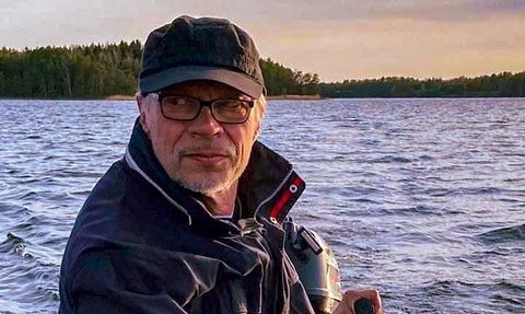 Kirjailija Juha Ruusuvuori ajaa perämoottoriveneellä merellisessä maisemassa