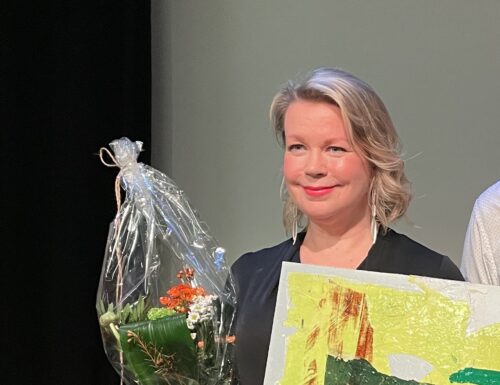 Elina Hirvonen kukkakimpun ja taideteoksen kanssa palkintotilaisuudessa