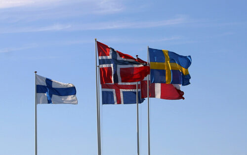 Pohjoismaiden liput liehuvat lipputangoissa sinistä taivasta vasten
